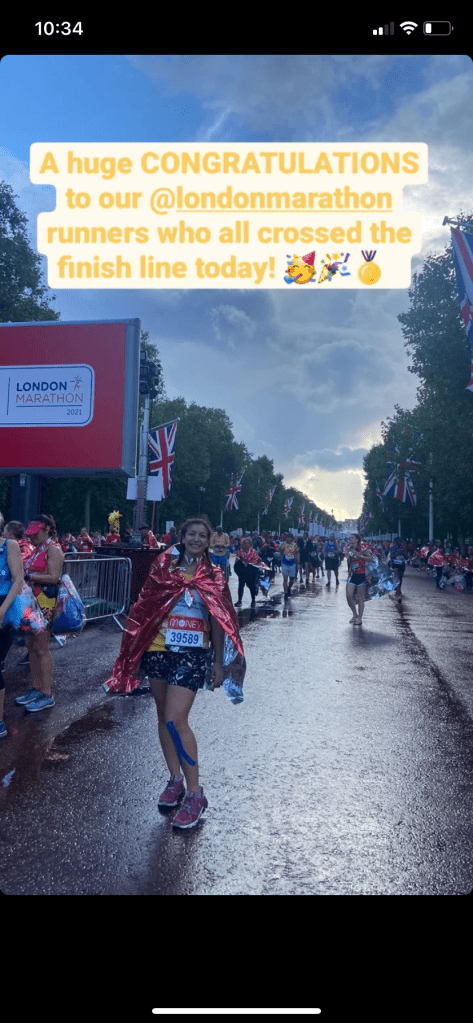 A post from Instagram of a woman at the end of the London Marathon wearing a red foil blanket with The Mall behind her