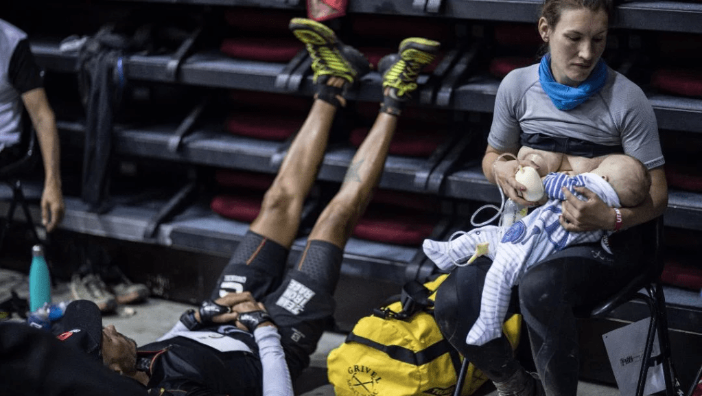 Sophie Power breastfeeding her young baby with a man stretching his legs next to her