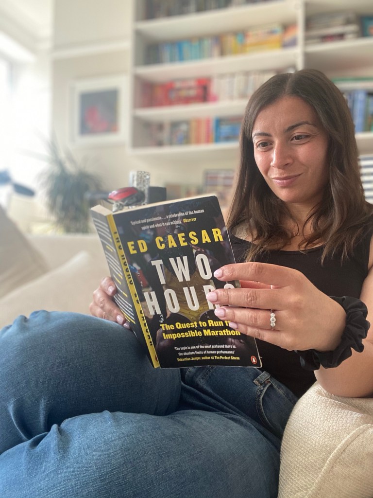 Woman sitting on a sofa reading the book 'Two Hours' by Ed Caesar