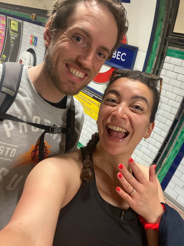 Man and woman wearing an engagement ring standing on the platform of Tooting Bec London Underground station