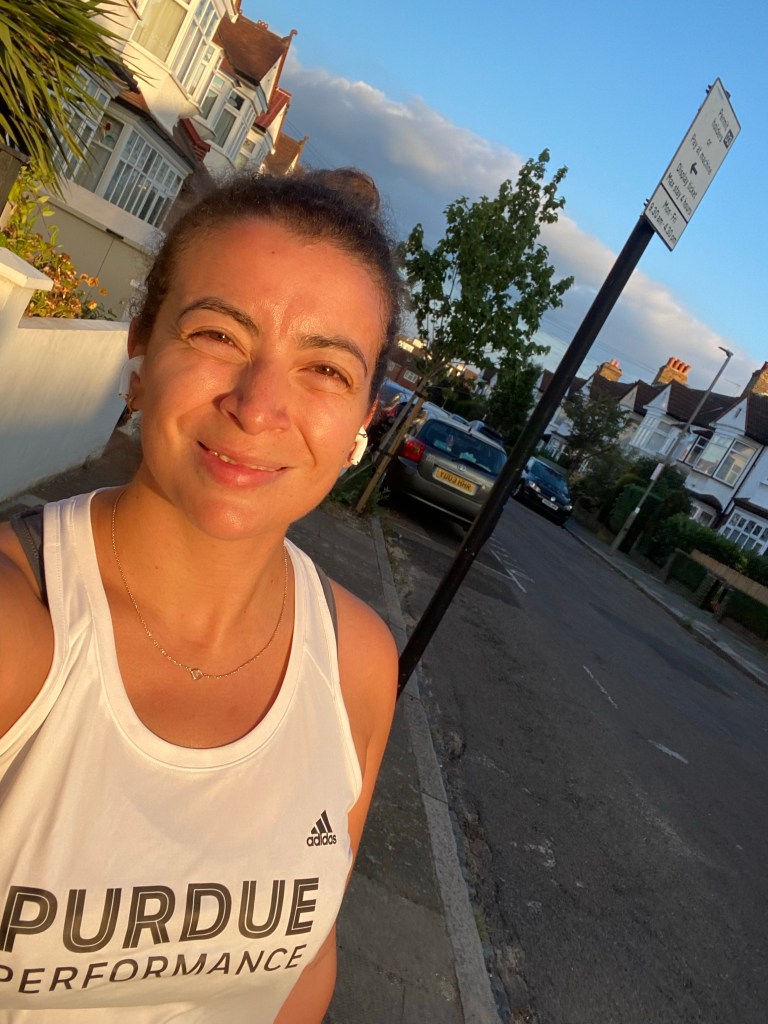 Girl on a London street wearing a white Adidas vest top from coaching company Purdue Performance