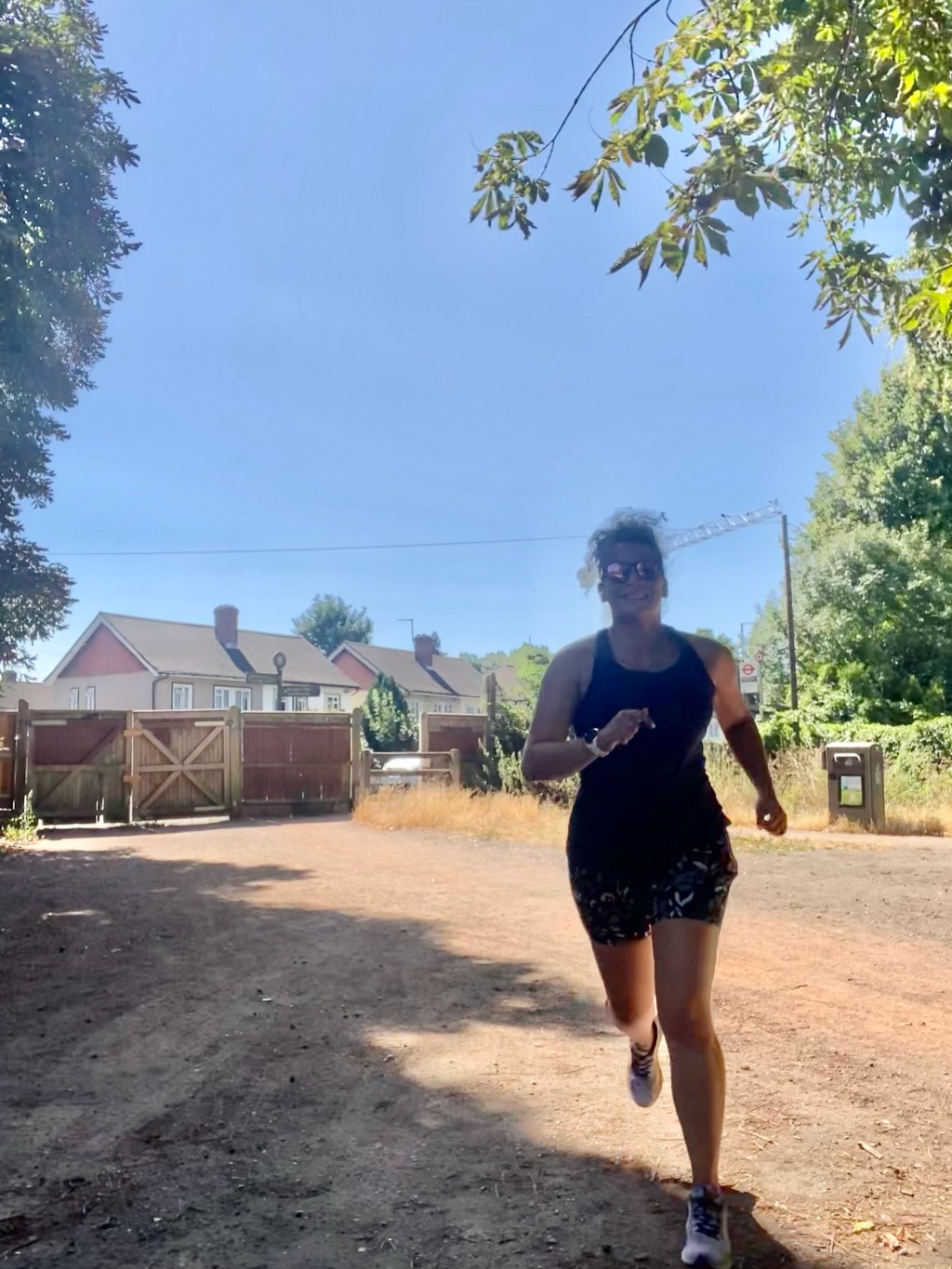 Girl running in shorts and a vest top in Morden Hall Park, London in the summer