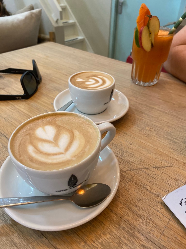 Image of two coffees in white cups on a wooden coffee table