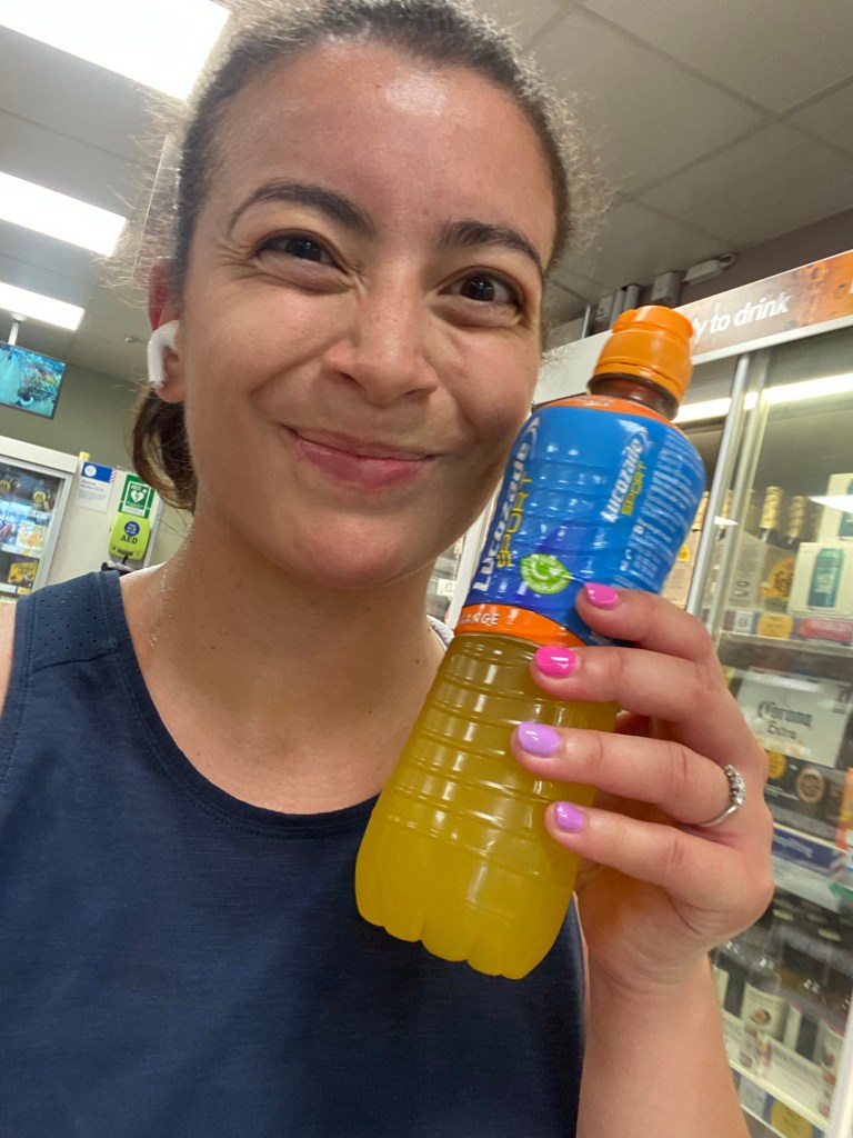Photo of a girl smiling holding a Lucozade orange energy drink