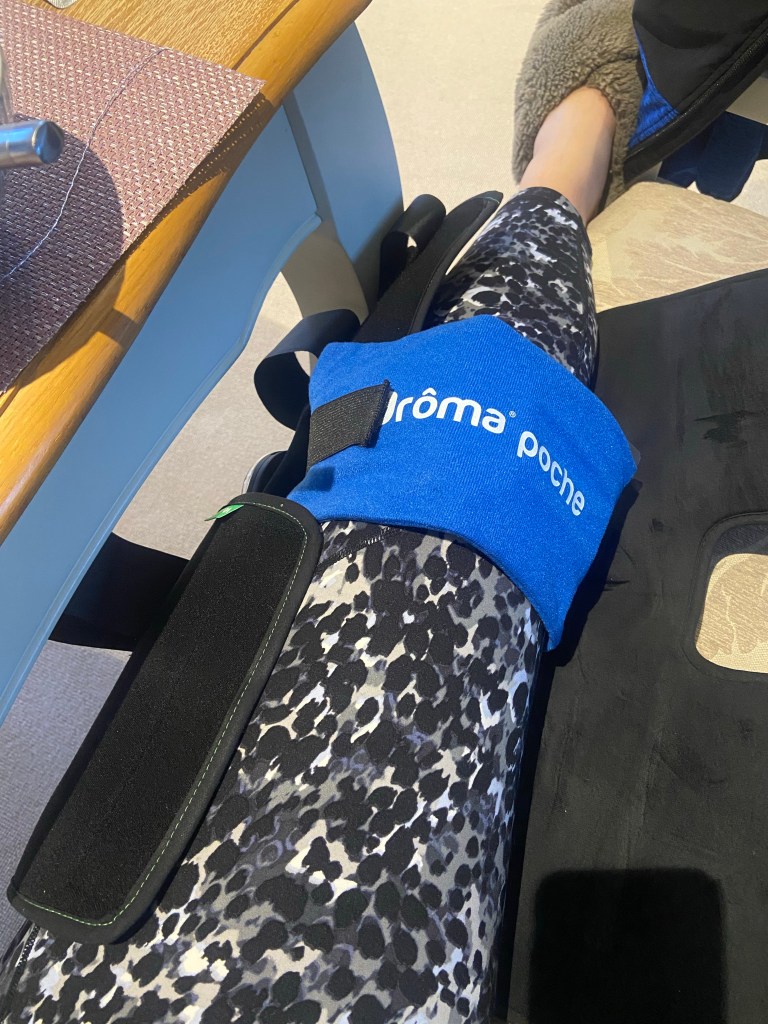 A photo of a leg with a knee brace on it and an ice pack strapped around it