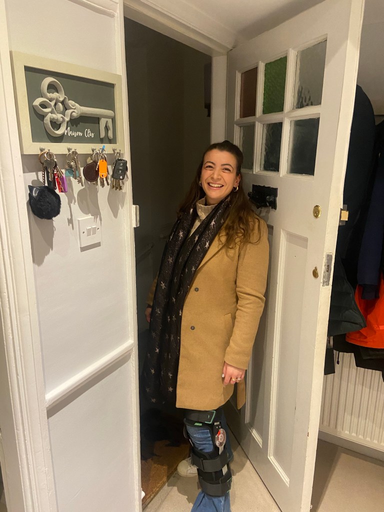 Image of girl at a front door smiling wearing a knee brace to protect a knee injury